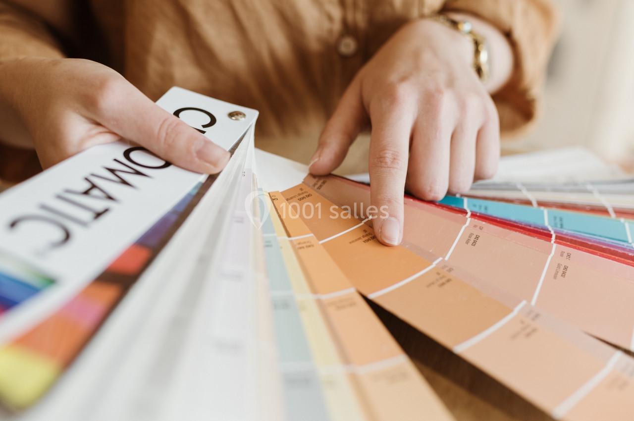 Une personne consulte un nuancier de couleurs, pointant une teinte orange parmi plusieurs échantillons.