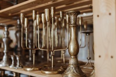 Miniature Service location Bougeoirs en laiton et en métal argenté alignés sur des étagères en bois dans un espace de rangement.