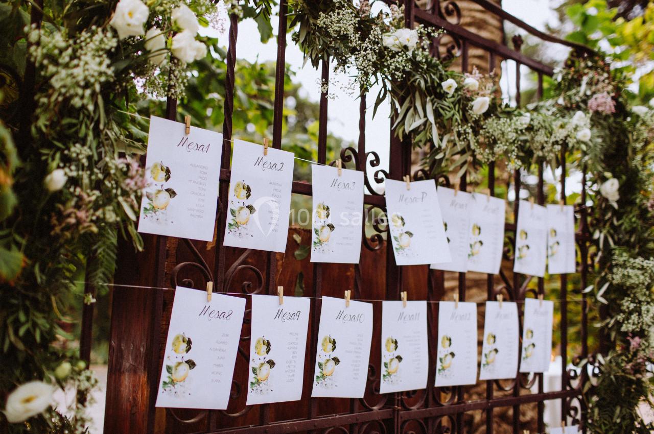 Feuilles de menus suspendues à une grille en métal décorée de fleurs et de verdure.