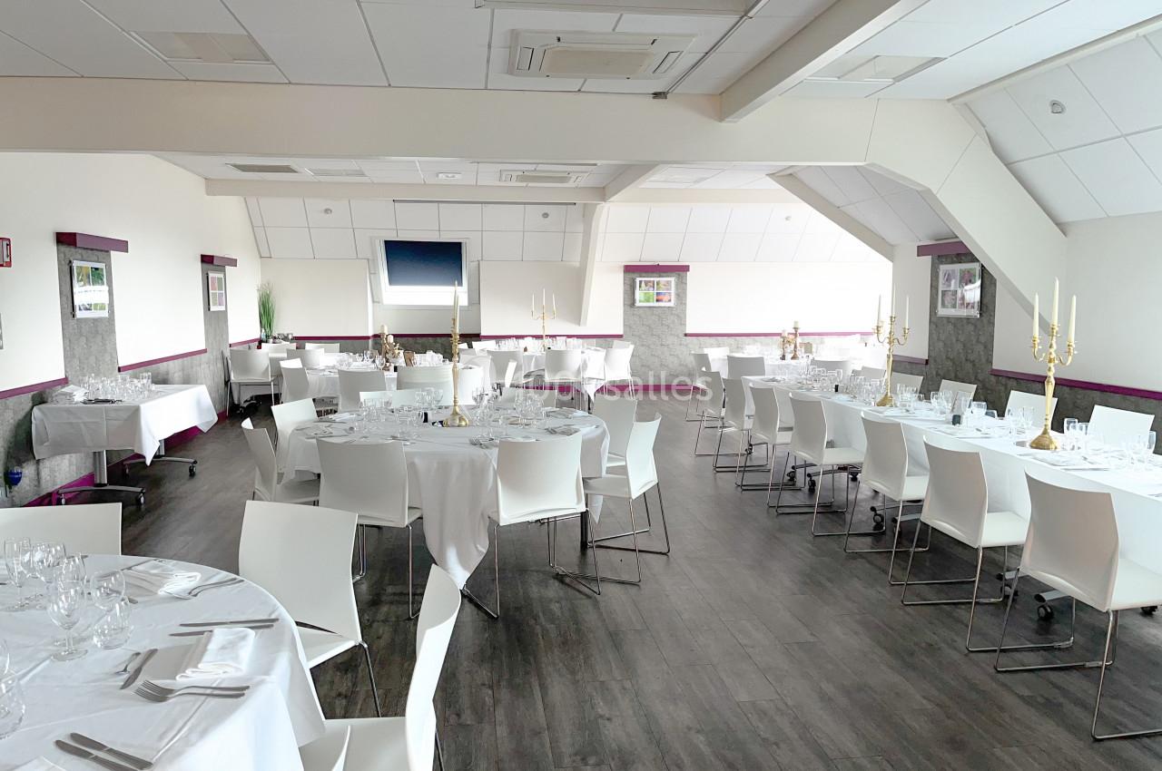 Salle de réception lumineuse avec tables rondes et rectangulaires dressées, chaises blanches et décorations élégantes.