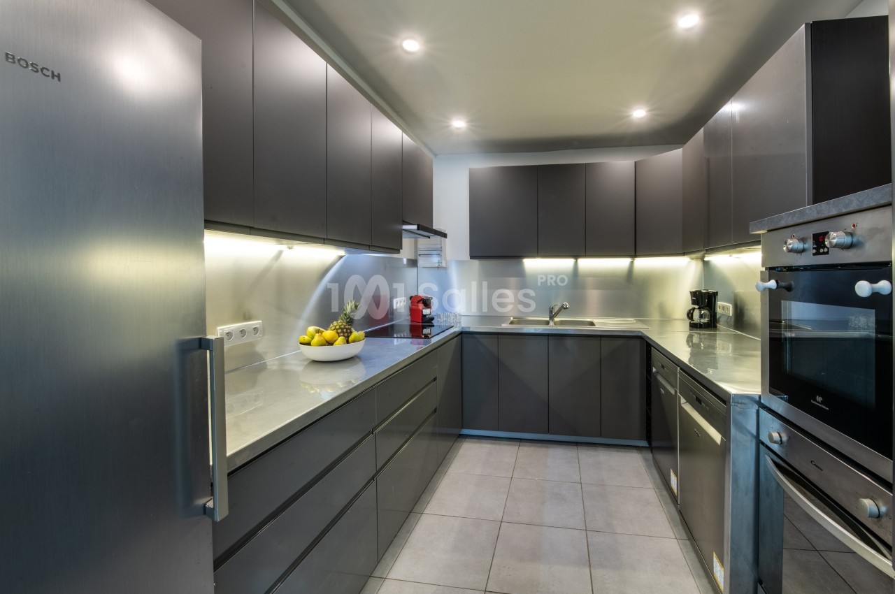 Cuisine moderne avec meubles gris, plan de travail clair, électroménagers intégrés et éclairage encastré.