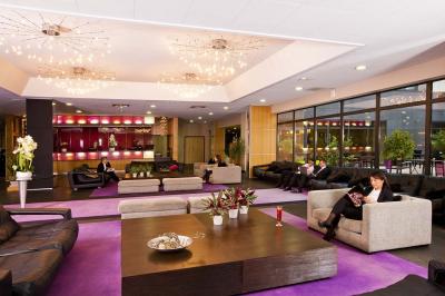 Salle de conférence avec des rangées de chaises grises et jaunes, une scène et une voiture en arrière-plan.