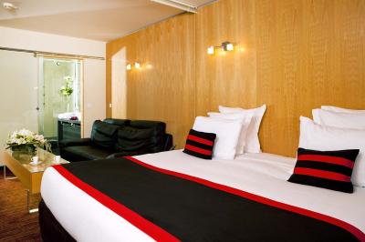 Salle de conférence avec des rangées de chaises grises et jaunes, une scène et une voiture en arrière-plan.