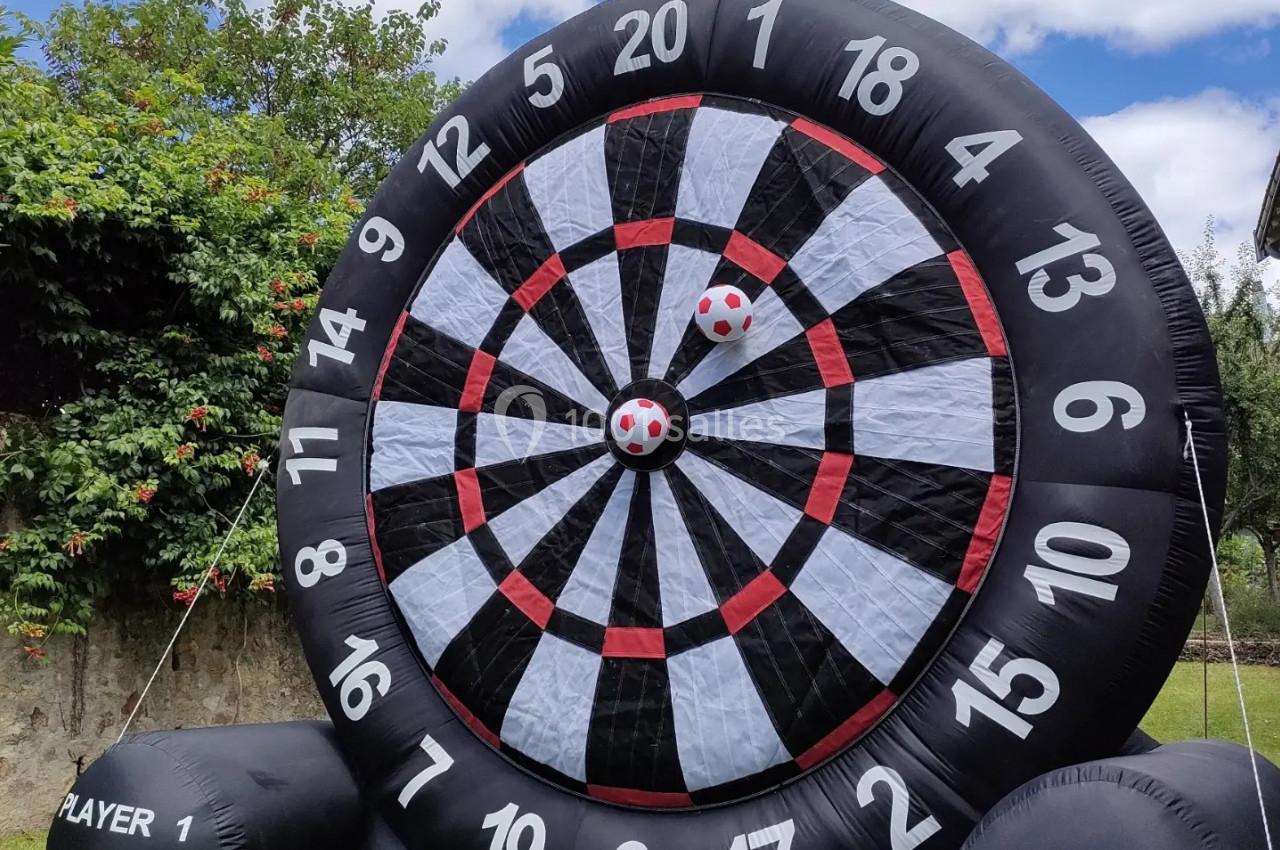 Cible géante gonflable en extérieur avec deux balles rouges et blanches fixées au centre.