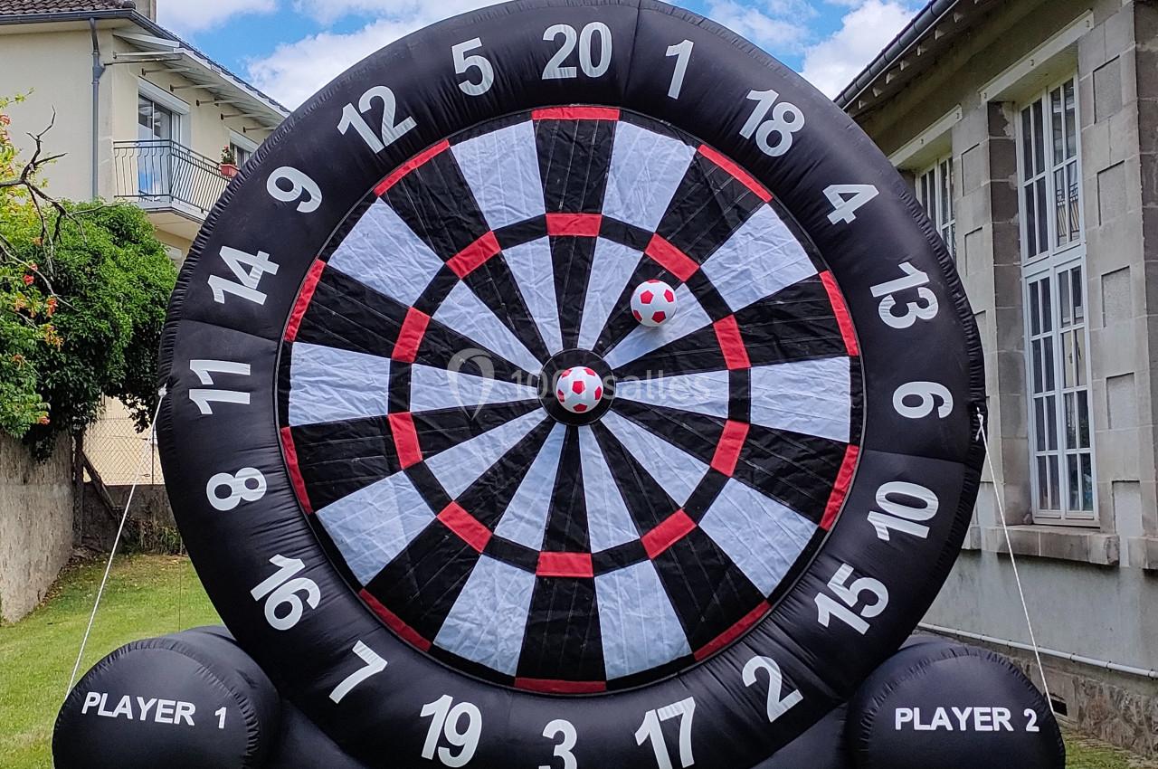 Cible géante gonflable de jeu de fléchettes avec deux balles à scratch fixées au centre, installée dans un jardin.