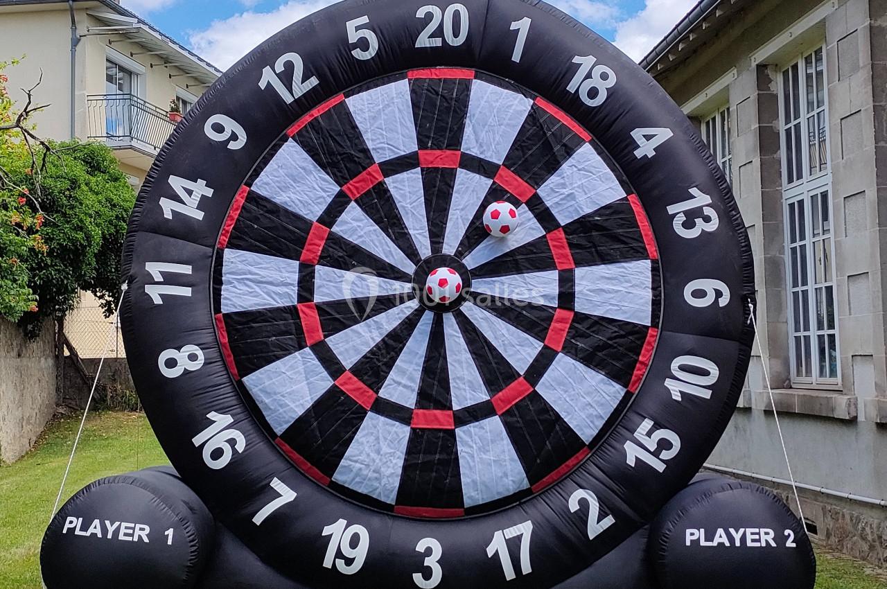 Cible géante gonflable noire et blanche avec des numéros, installée dans un jardin près d'un bâtiment.