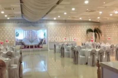 Salle de réception élégante avec tables dressées, chaises décorées et une estrade ornée de rideaux lumineux.