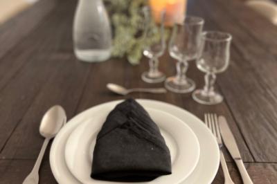 Miniature My Event Pro #1 Table dressée avec une assiette blanche, une serviette noire pliée, des couverts, des verres et une carafe d'eau.