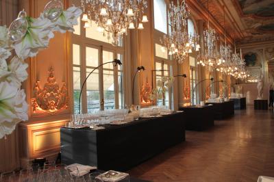 Salle de réception avec de longues tables dressées pour un événement, éclairée par des lumières chaudes.