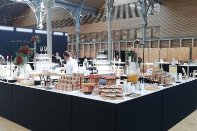 Salle de réception avec de longues tables dressées pour un événement, éclairée par des lumières chaudes.