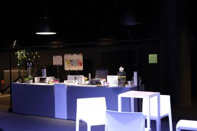 Salle de réception avec de longues tables dressées pour un événement, éclairée par des lumières chaudes.