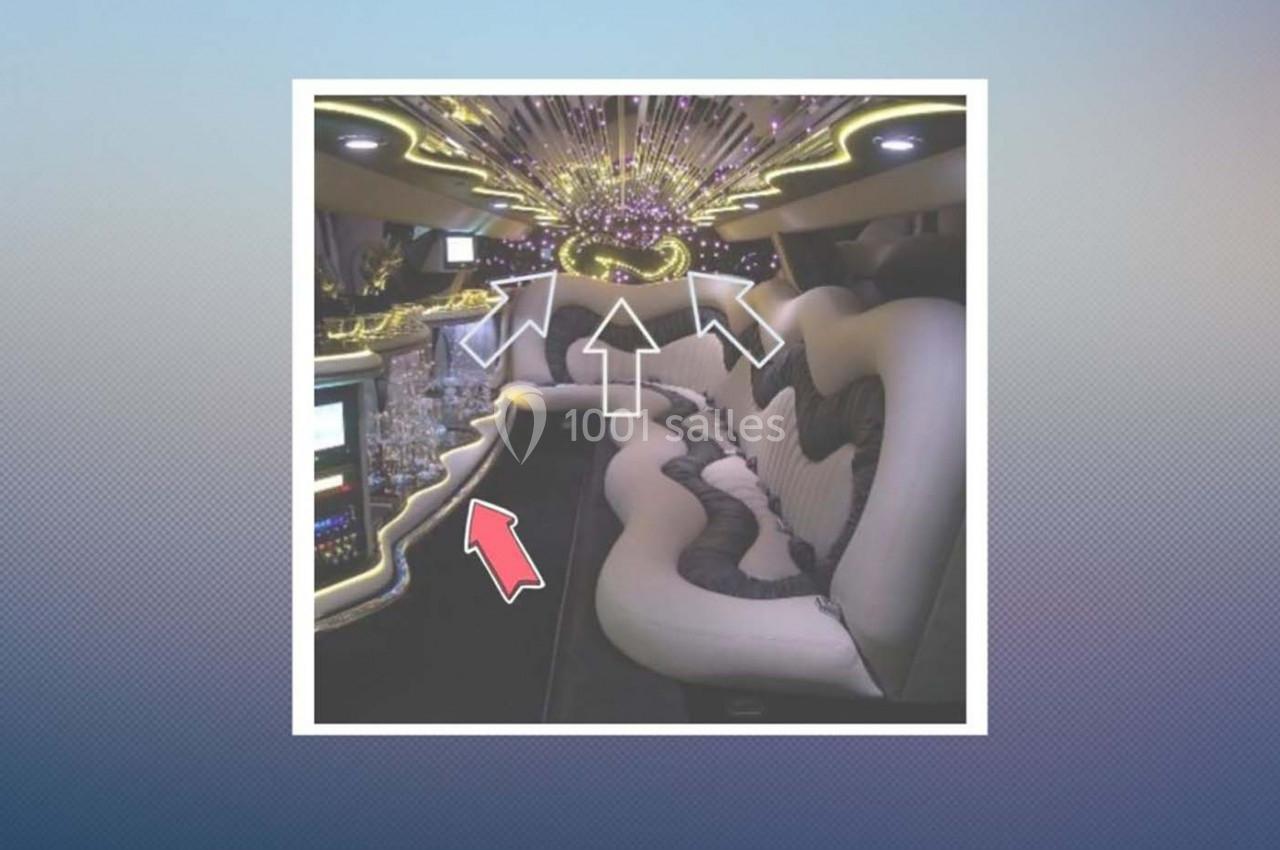 Intérieur d'une limousine avec sièges en cuir blanc, éclairage LED coloré et bar intégré.