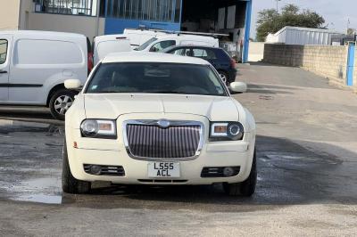 Limousine blanche sur une plateforme éclairée par des néons roses avec le texte ’Offre exclusive’ et un prix affiché.