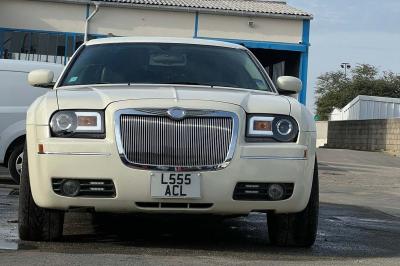 Limousine blanche sur une plateforme éclairée par des néons roses avec le texte ’Offre exclusive’ et un prix affiché.