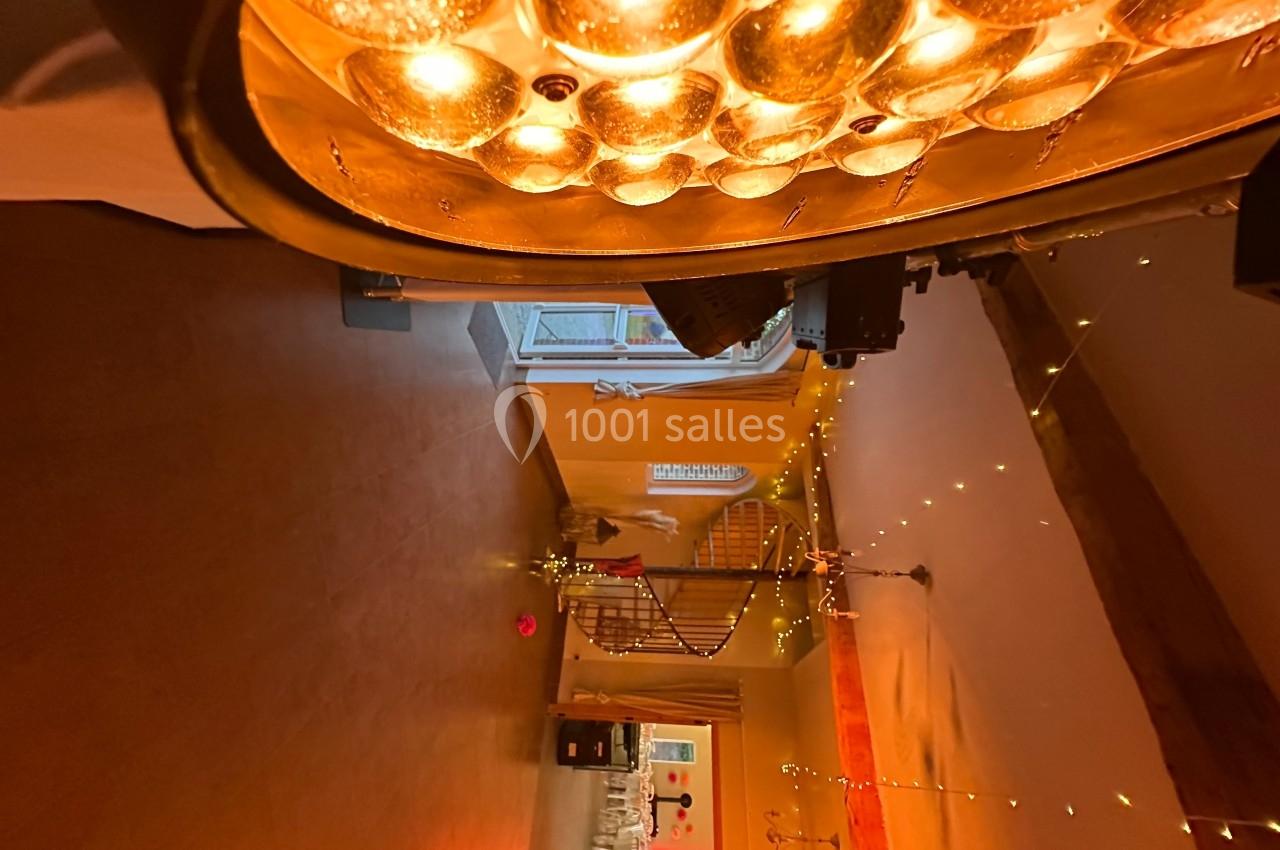 L'intérieur d'une pièce chaleureusement éclairée avec des guirlandes lumineuses et un lustre doré au plafond.