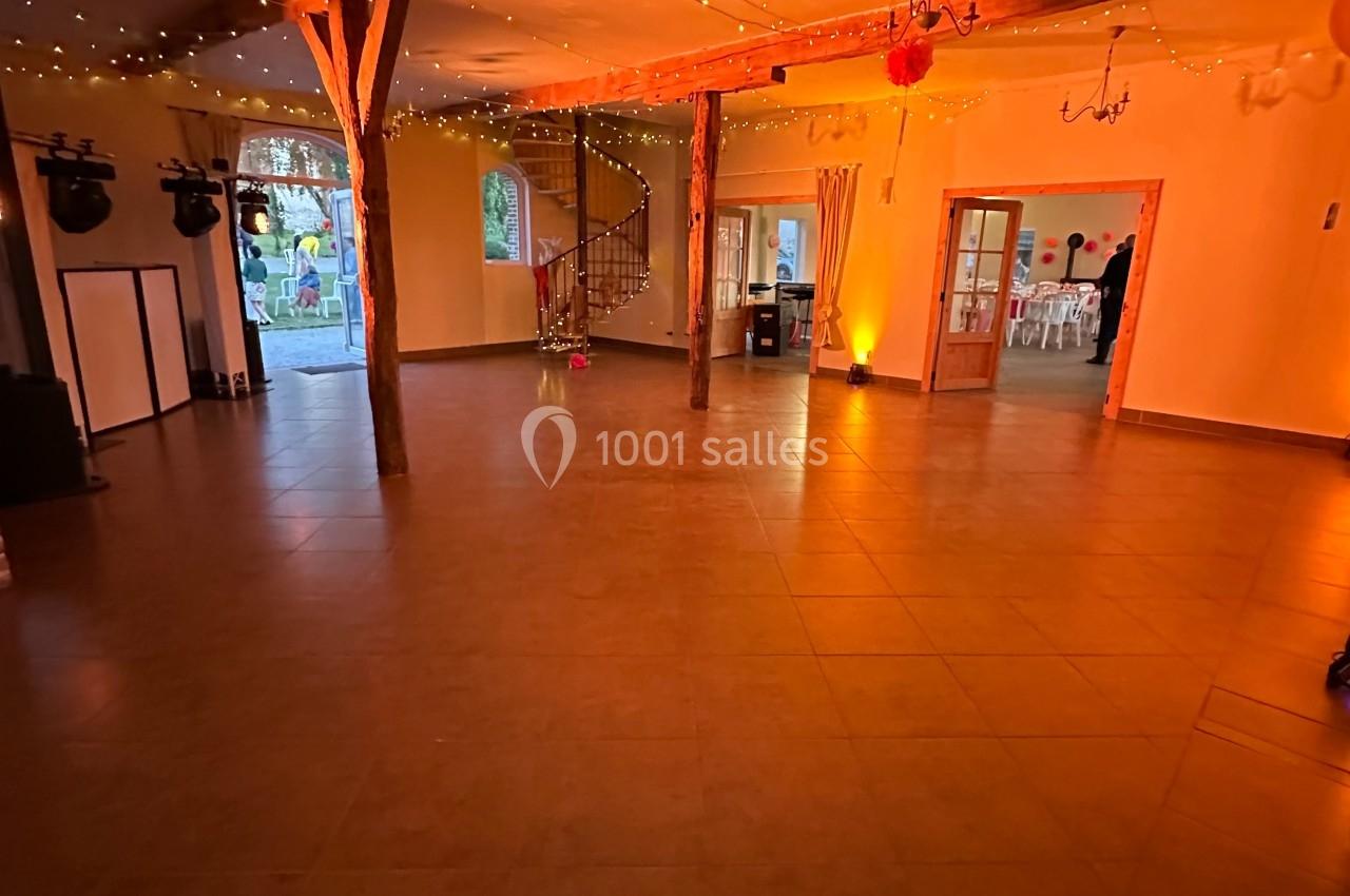 Salle spacieuse avec poutres apparentes, éclairage chaleureux, décorations lumineuses et ballon rouge suspendu.