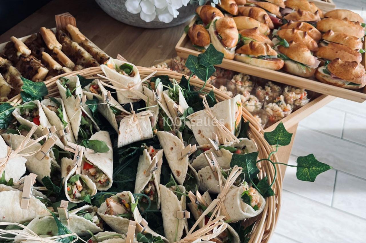 Plateau de wraps garnis et assortiments de sandwiches et bouchées apéritives disposés sur une table en bois.