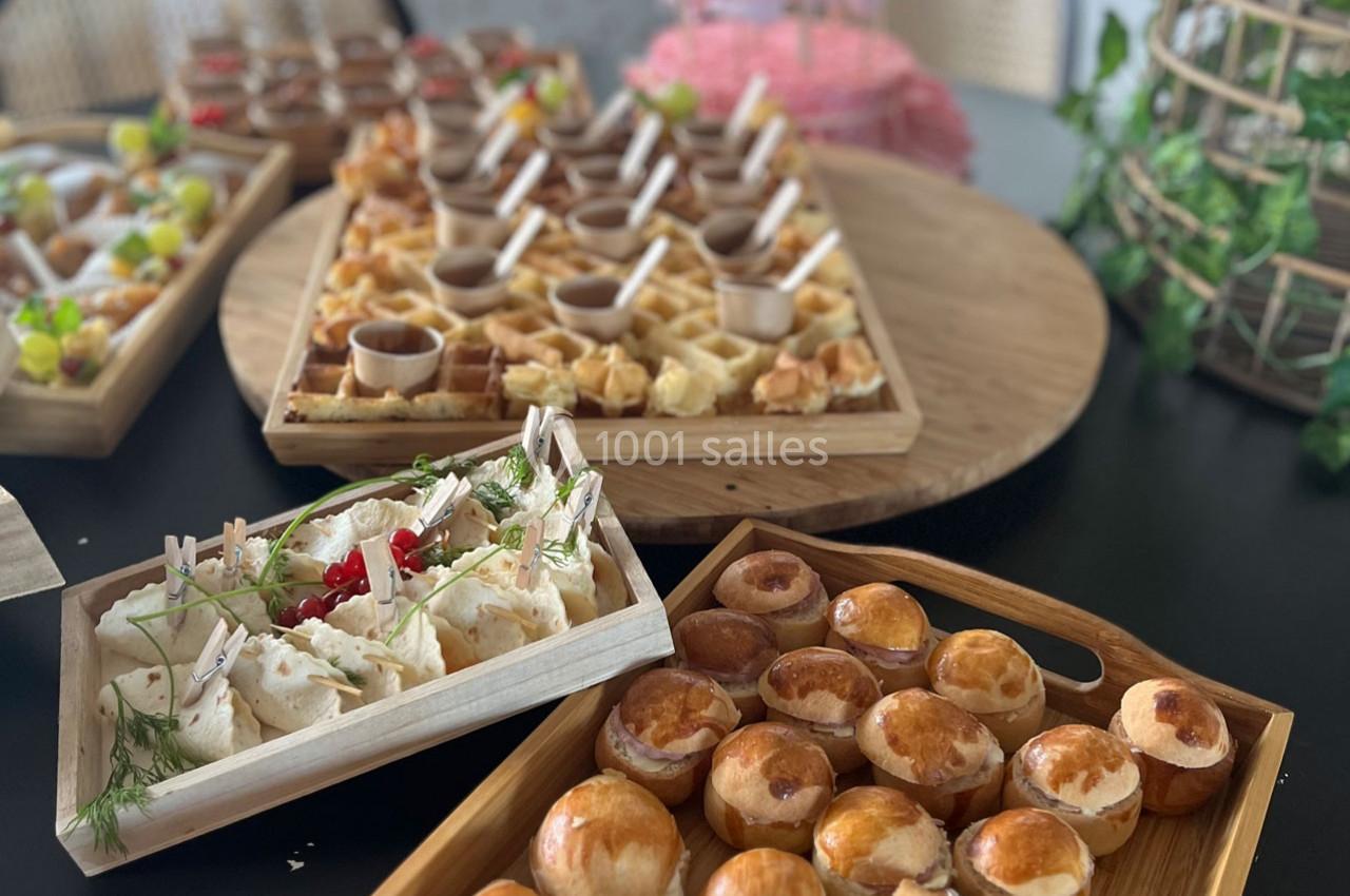 Plateaux en bois garnis de bouchées sucrées et salées, disposés sur une table pour un buffet ou un apéritif.