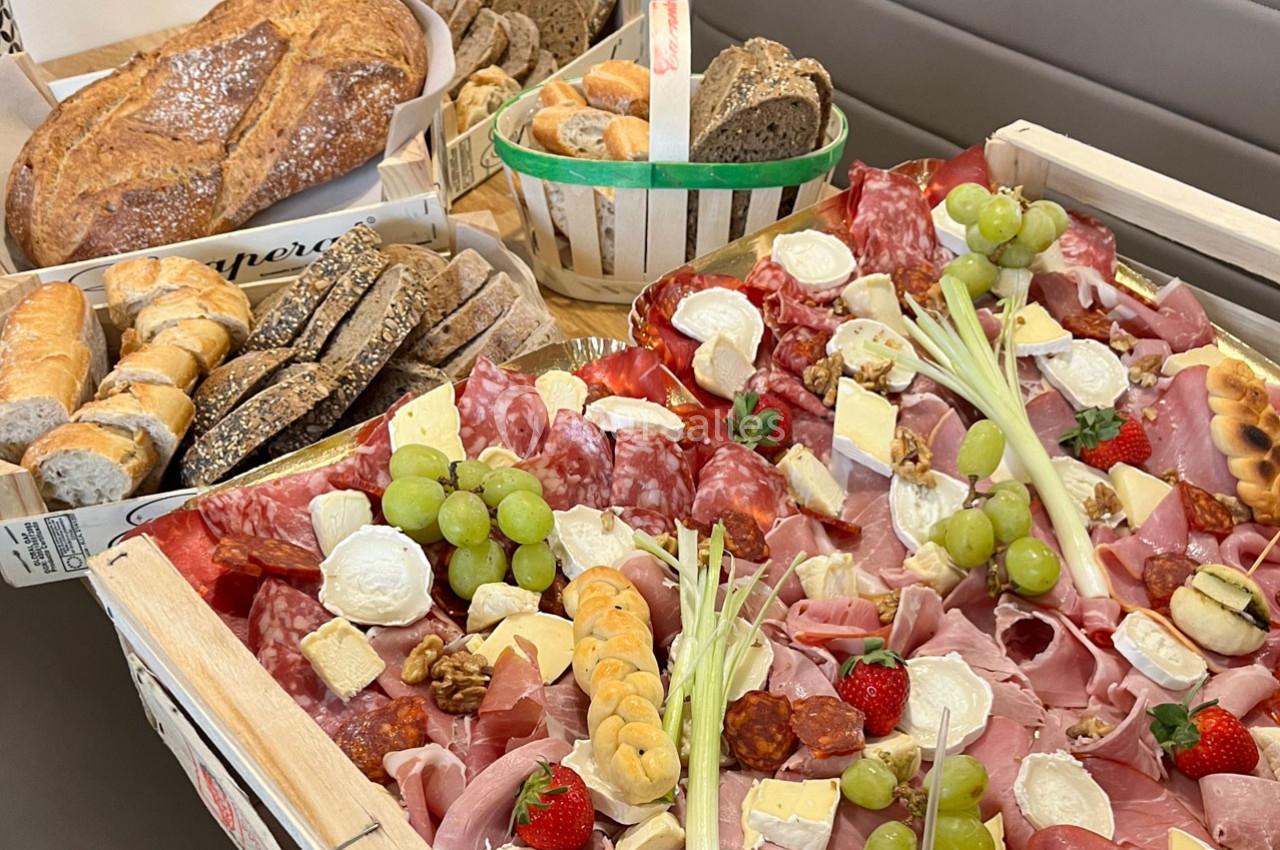 Plateau de charcuteries, fromages, fruits et pains variés disposés sur une table pour un buffet.
