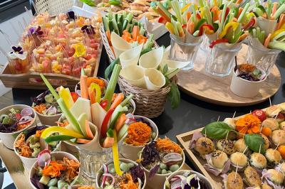Des portions de nourriture servies dans des pots en carton avec des fleurs blanches en décoration.