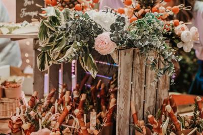 Des portions de nourriture servies dans des pots en carton avec des fleurs blanches en décoration.