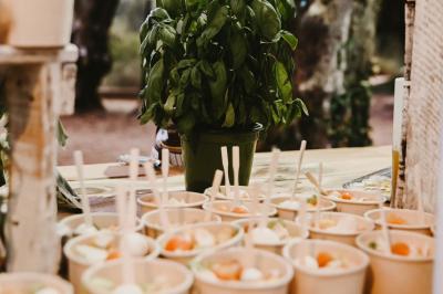 Des portions de nourriture servies dans des pots en carton avec des fleurs blanches en décoration.