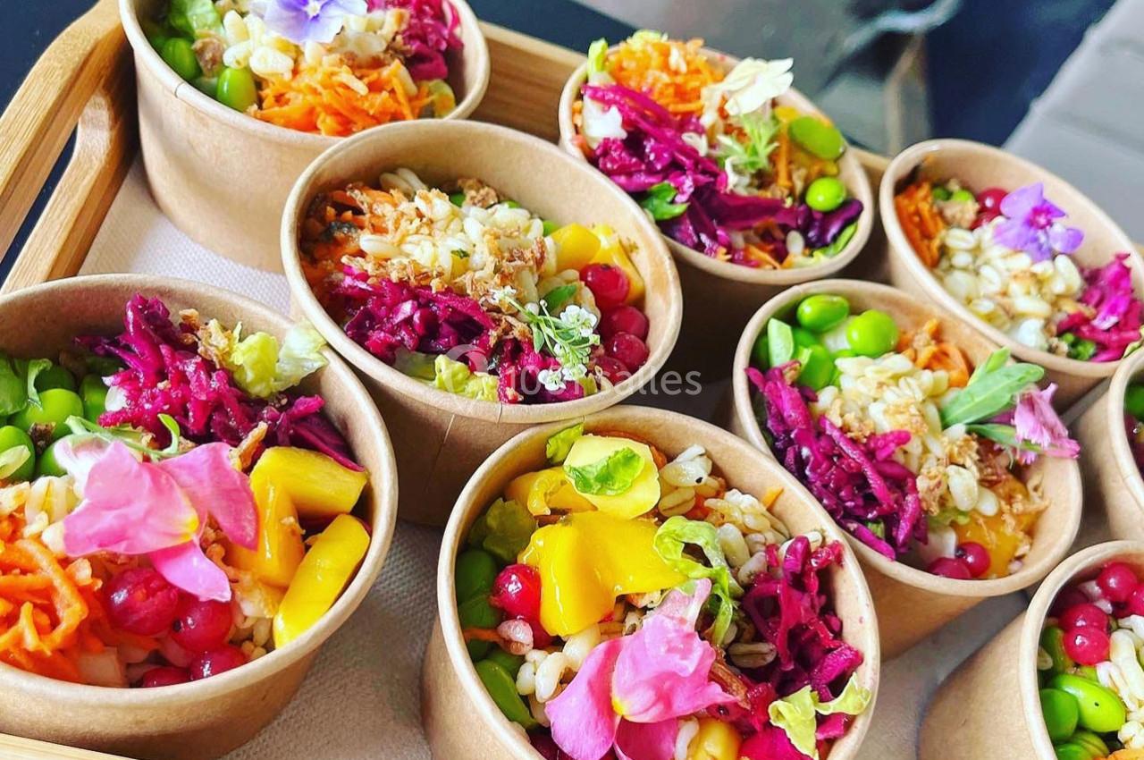 Assortiment de bols en carton contenant des salades colorées garnies de légumes, fruits et fleurs comestibles.