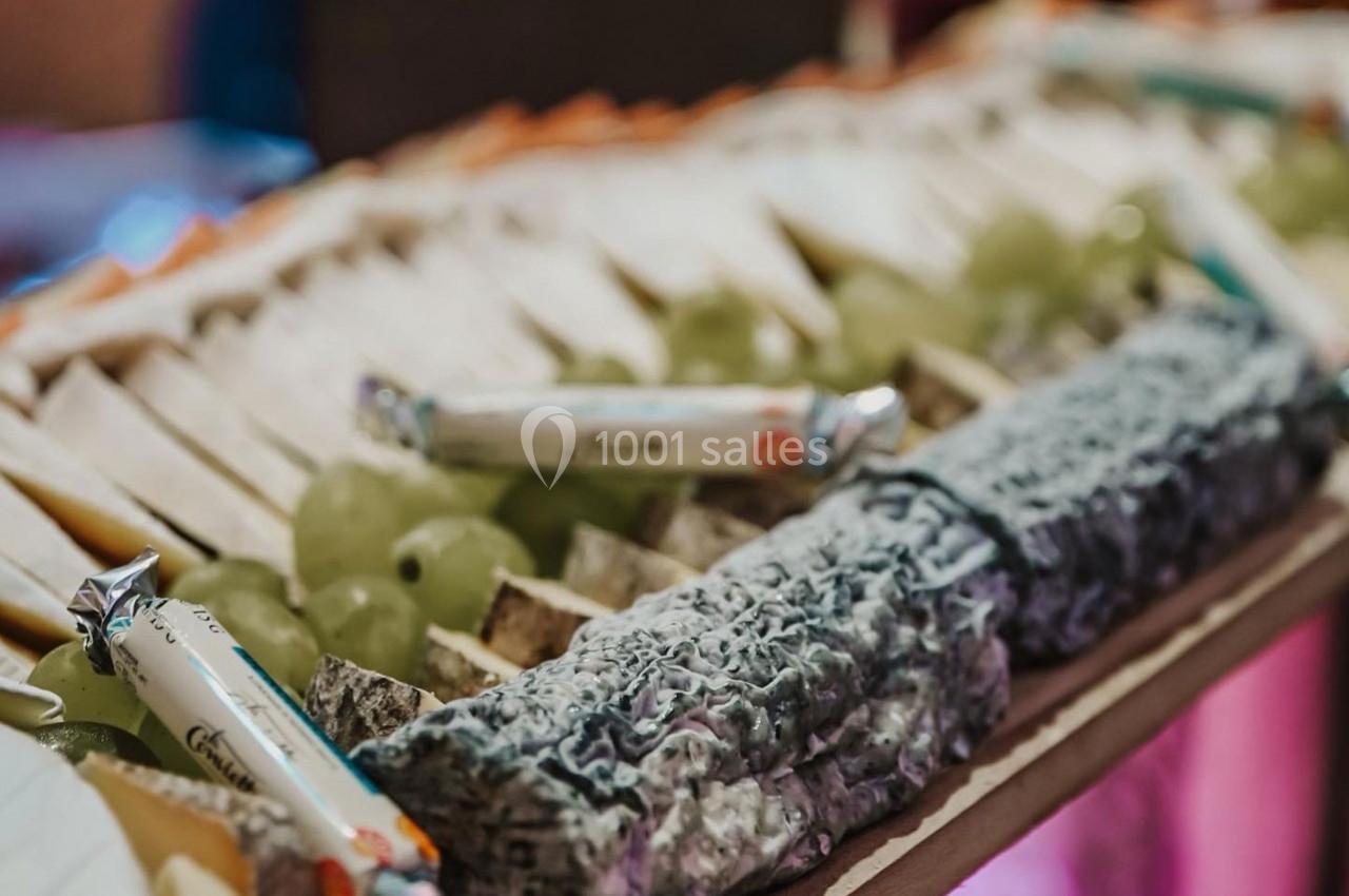 Plateau de fromages variés avec raisins verts et emballages de biscuits, présenté sur une table.