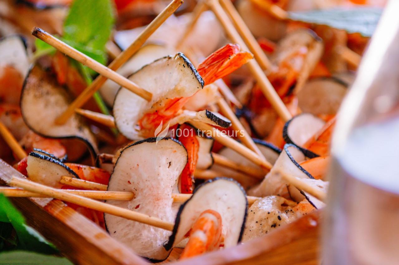 Brochettes de crevettes et de légumes grillés, présentées dans un plat en bois avec des herbes en arrière-plan.