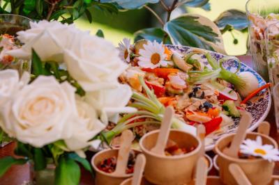 Des portions de nourriture servies dans des pots en carton avec des fleurs blanches en décoration.
