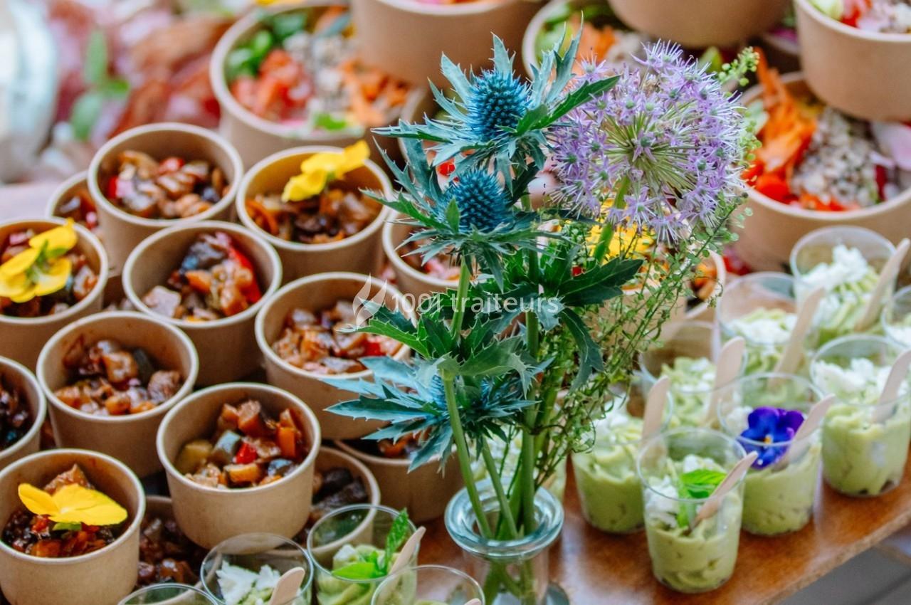 Plats variés présentés dans des contenants individuels avec un bouquet de fleurs en premier plan.