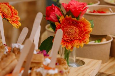 Des portions de nourriture servies dans des pots en carton avec des fleurs blanches en décoration.