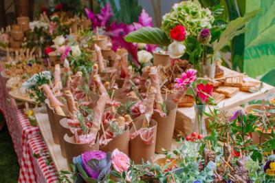 Des portions de nourriture servies dans des pots en carton avec des fleurs blanches en décoration.
