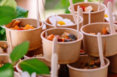 Des portions de nourriture servies dans des pots en carton avec des fleurs blanches en décoration.