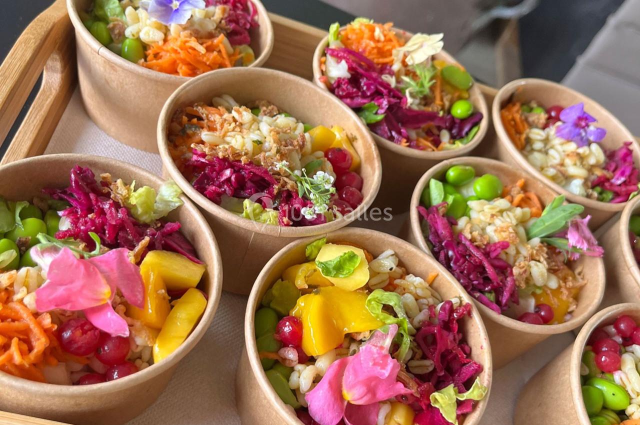 Assortiment de bols en carton contenant des salades colorées garnies de fleurs comestibles et de légumes variés.