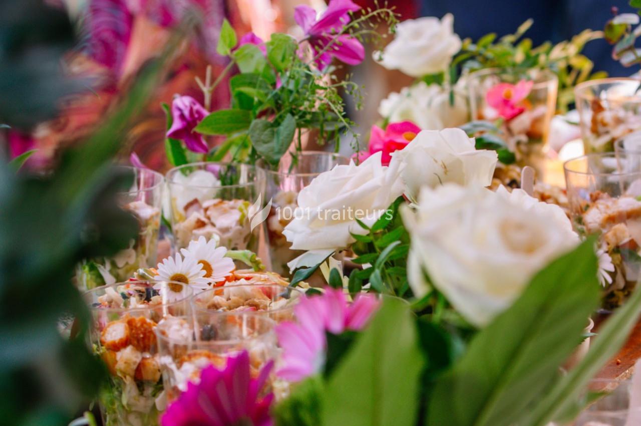Arrangement de fleurs colorées et verres disposés sur une table lors d'un événement en extérieur.