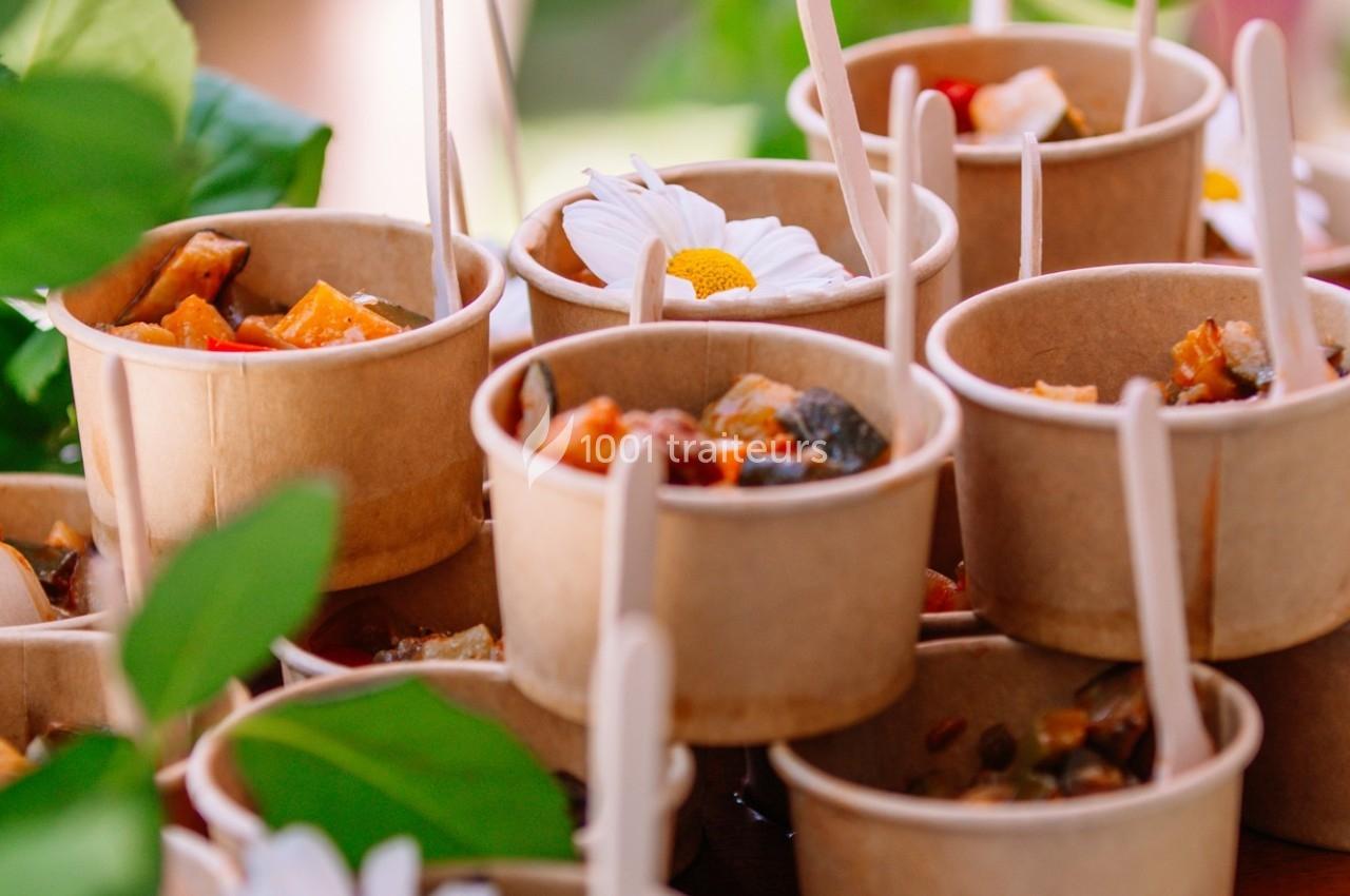Des portions de nourriture servies dans des pots en carton avec des fleurs blanches en décoration.