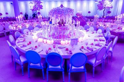 Piscine éclairée de nuit entourée de chaises longues, avec une terrasse en premier plan et des bougies allumées.