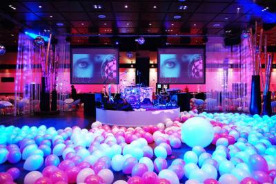 Piscine éclairée de nuit entourée de chaises longues, avec une terrasse en premier plan et des bougies allumées.