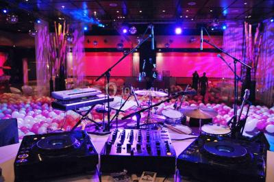 Piscine éclairée de nuit entourée de chaises longues, avec une terrasse en premier plan et des bougies allumées.