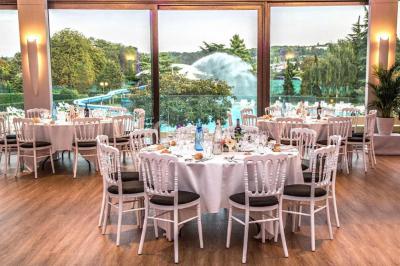 Piscine éclairée de nuit entourée de chaises longues, avec une terrasse en premier plan et des bougies allumées.