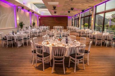 Piscine éclairée de nuit entourée de chaises longues, avec une terrasse en premier plan et des bougies allumées.