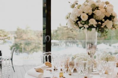 Piscine éclairée de nuit entourée de chaises longues, avec une terrasse en premier plan et des bougies allumées.