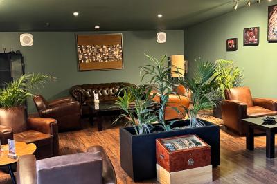 Coucher de soleil rougeoyant derrière une rangée d'arbres, vu depuis une terrasse avec mobilier et voitures garées.