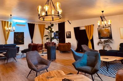 Coucher de soleil rougeoyant derrière une rangée d'arbres, vu depuis une terrasse avec mobilier et voitures garées.