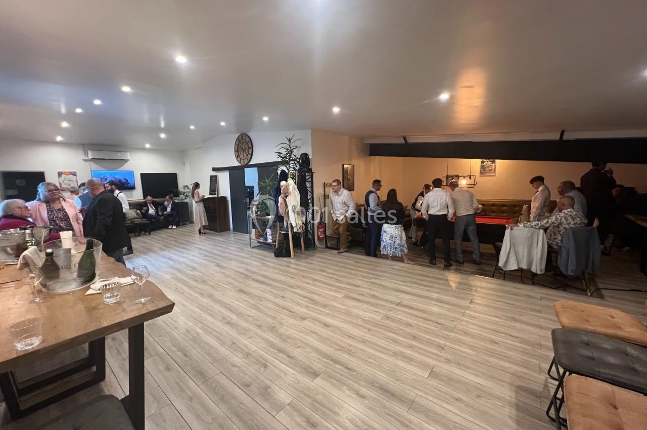 Groupe de personnes discutant et se réunissant dans une grande salle lumineuse avec un sol en bois clair.