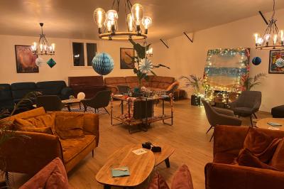 Coucher de soleil rougeoyant derrière une rangée d'arbres, vu depuis une terrasse avec mobilier et voitures garées.