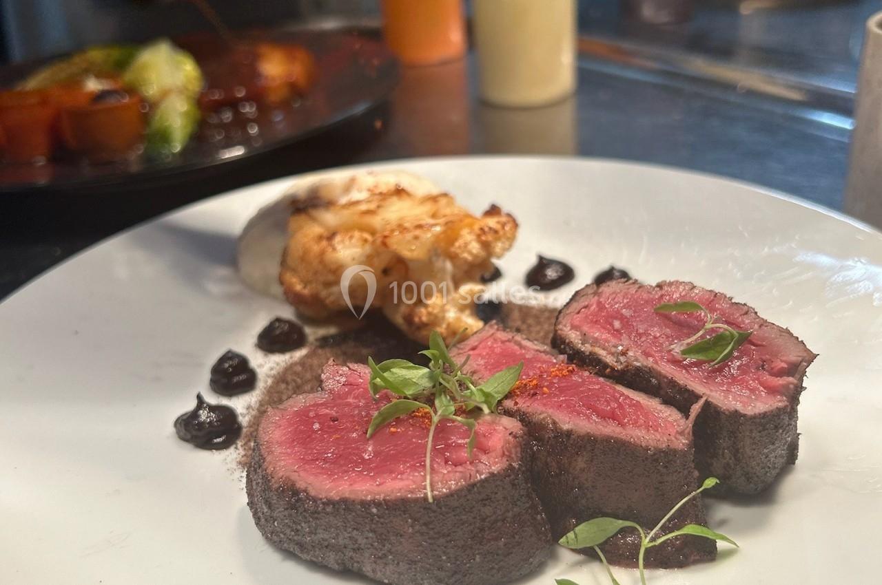 Assiette gastronomique avec filet de viande saignante, purée, chou-fleur rôti et sauce, dressée dans une cuisine…