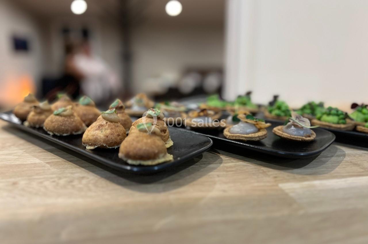 Plateaux de bouchées apéritives variées disposés sur une table en bois dans un environnement intérieur lumineux.