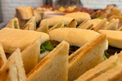 Coucher de soleil rougeoyant derrière une rangée d'arbres, vu depuis une terrasse avec mobilier et voitures garées.